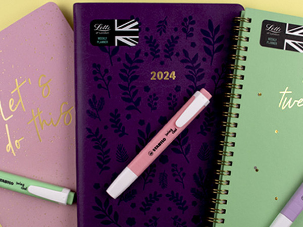 A pink, purple and green 2024 planner with coordinating highlighters on a yellow background.