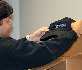 A staff member checks a hat before shipping it at the U of A Bookstore.