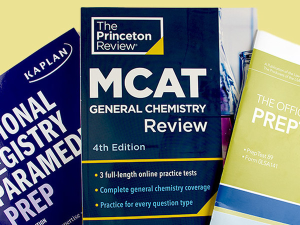 Various test prep books, including MCAT, are spread out on a yellow background.